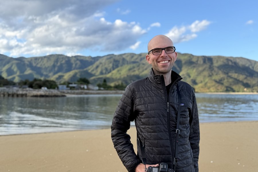 Aaron Jokela on a beach, holding a camera